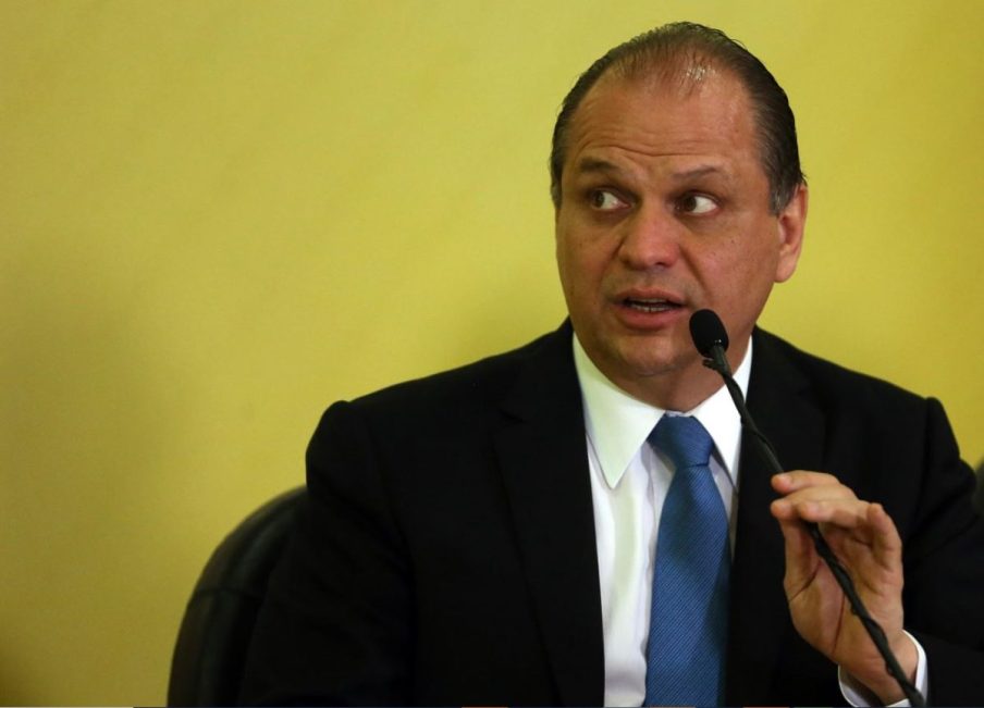 Foto do deputado federal Ricardo Barros falando em um microfone à frente de um fundo de cor amarela