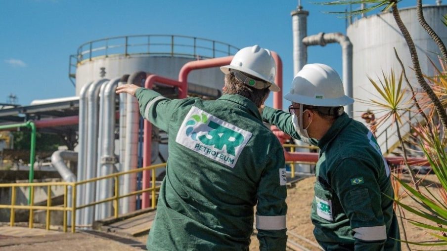 Foto de dois funcionários da 3R Petroleum, vestindo uniforme verde e capacete branco. As ações da 3R (RRRP3) lideraram bloco de altas no Ibovespa em 17/05/2024