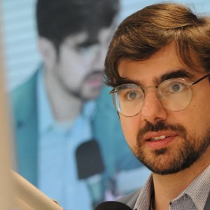 Foto de Guilherme Mello, secretário de política nacional da Fazenda. Ele é homem, tem cabelo e barba castanho-claro e usa óculos