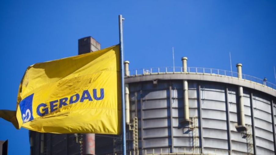 Foto de uma planta da Gerdau (GGBR4) com uma bandeira de fundo amarelo com logo azul da empresa.