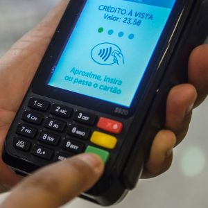 Foto de uma máquina de cartão de débito e crédito. Na tela, está escrito: "crédito à vista. Valor: 23,58"