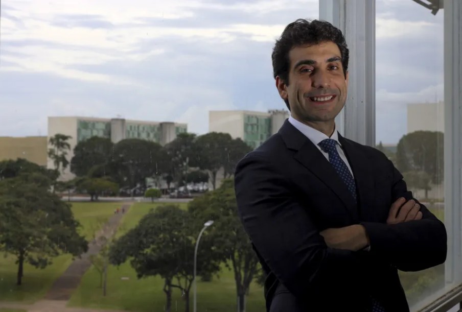 Foto de Gabriel Galípolo, Secretário Executivo da Fazenda do governo Lula. Ele é branco, tem cabelo castanho e veste um terno com gravata azul escura.