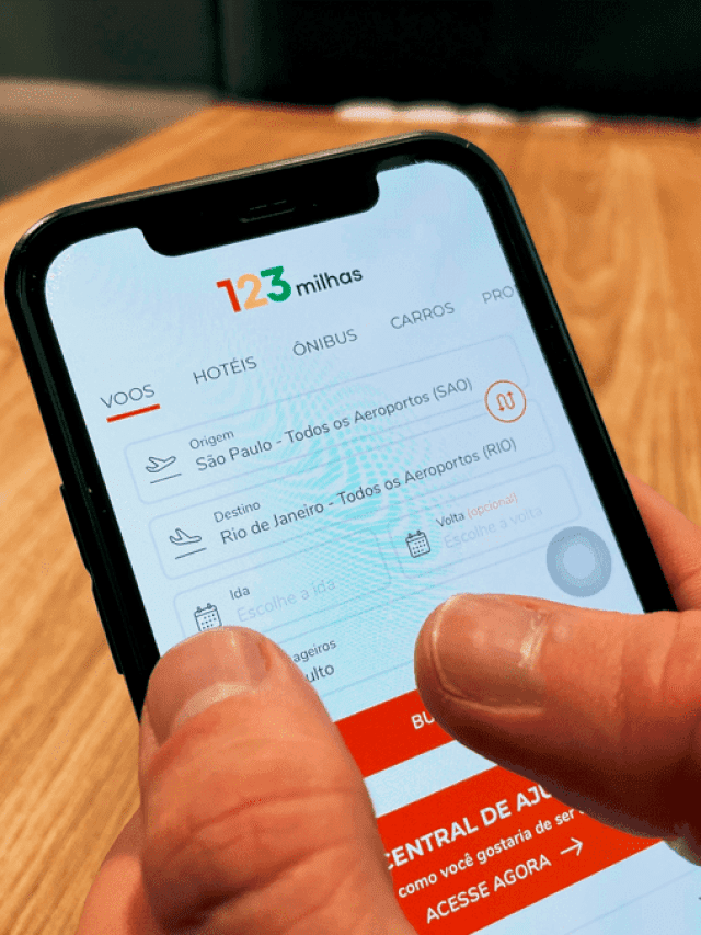 A imagem mostra uma mão segurando um celular, com o site da 123 milhas aberto na tela.