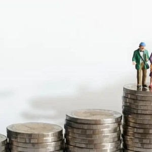Imagem de três montes de moedas, uma maior que a outra. A última delas e a maior tem um casal de idosos em formato de maquete.