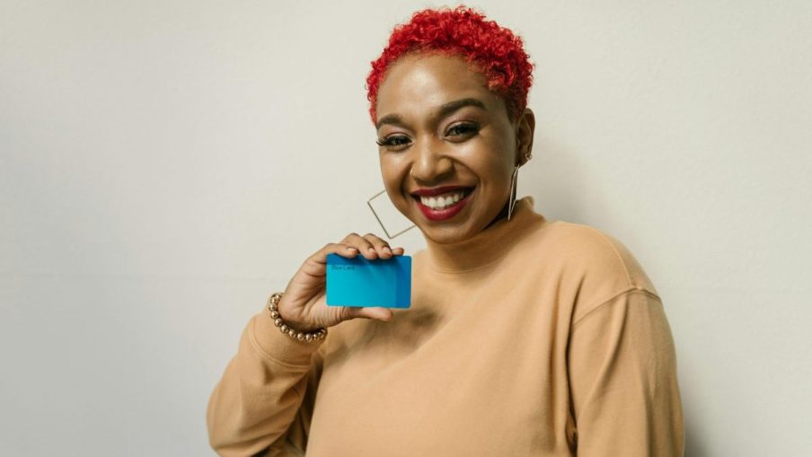 Mulher negra feliz e sorridente segurando um cartão de crédito