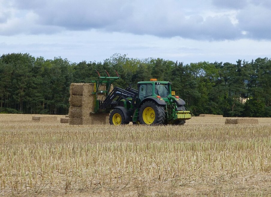 Imagem para matéria sobre investir no agronegócio em que aparece uma máquina agrícola em meio a uma plantação.