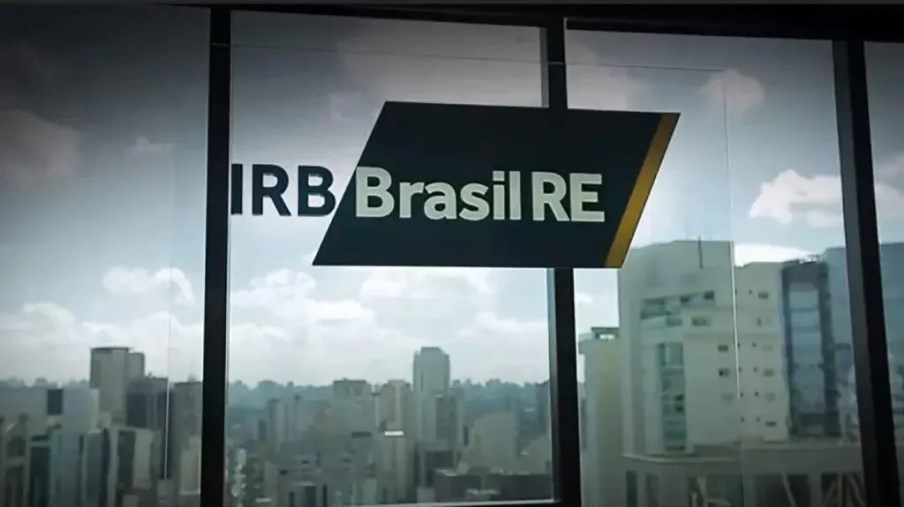 Foto do logo da IRB Brasil com paisagem ao fundo. A matéria lista as ações em alta em maio de 2024