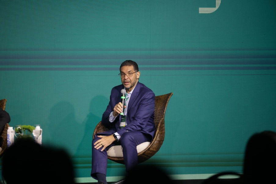 Foto de Mansueto Almeida, economista-chefe do BTG Pactual. Ele é homem, veste um terno azul escuro e fala ao microfone sentado em palestra. A matéria fala explica como mudanças climáticas afetam investimentos