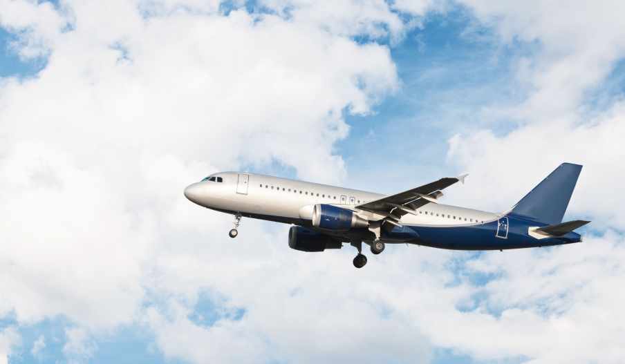 Foto de um avião azul e branco. Ele está sobrevoando em um céu azul.