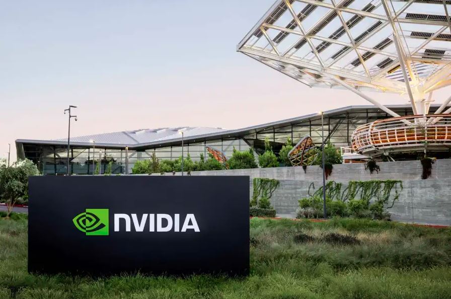 Imagem de uma placa preta em um gramado com o escrito "Nvidia". Atrás, a sede de uma empresa de tecnologia.