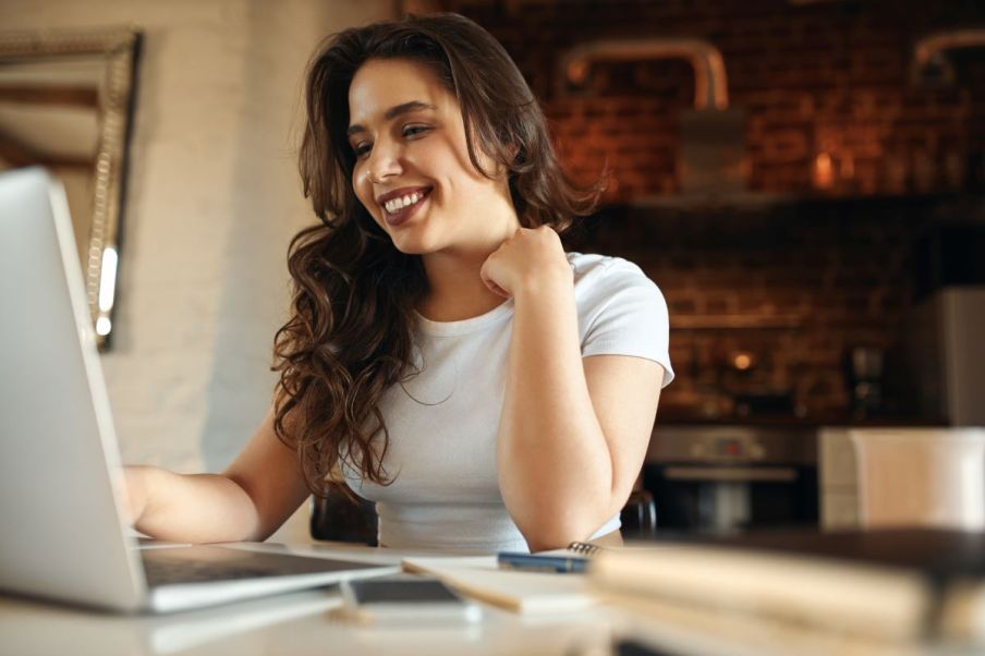 Imagem de uma mulher branca sorrindo em frente a um computador.