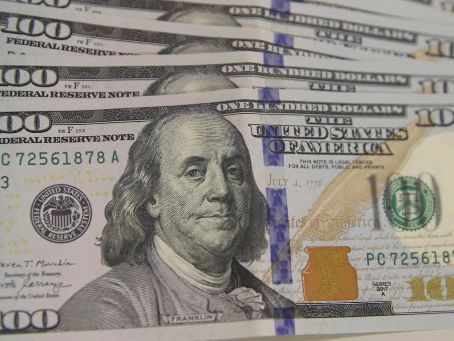 Foto de cédulas de US$ 100 (cem dólares). A matéria explica como gestoras de fundos do mercado financeiro estão divididas sobre o futuro da cotação do dólar para o real e encurtaram posições compradas na divisa americana após alta recorde em dezembro e queda em janeiro.