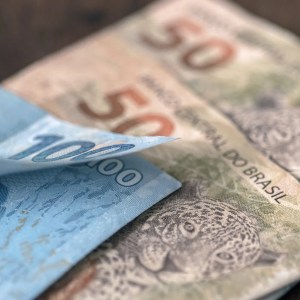 Foto de uma nota de 100 reais e duas de 50 reais.