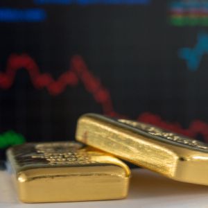 Imagem de duas barras de ouro e ao fundo gráficos do mercado financeiro.